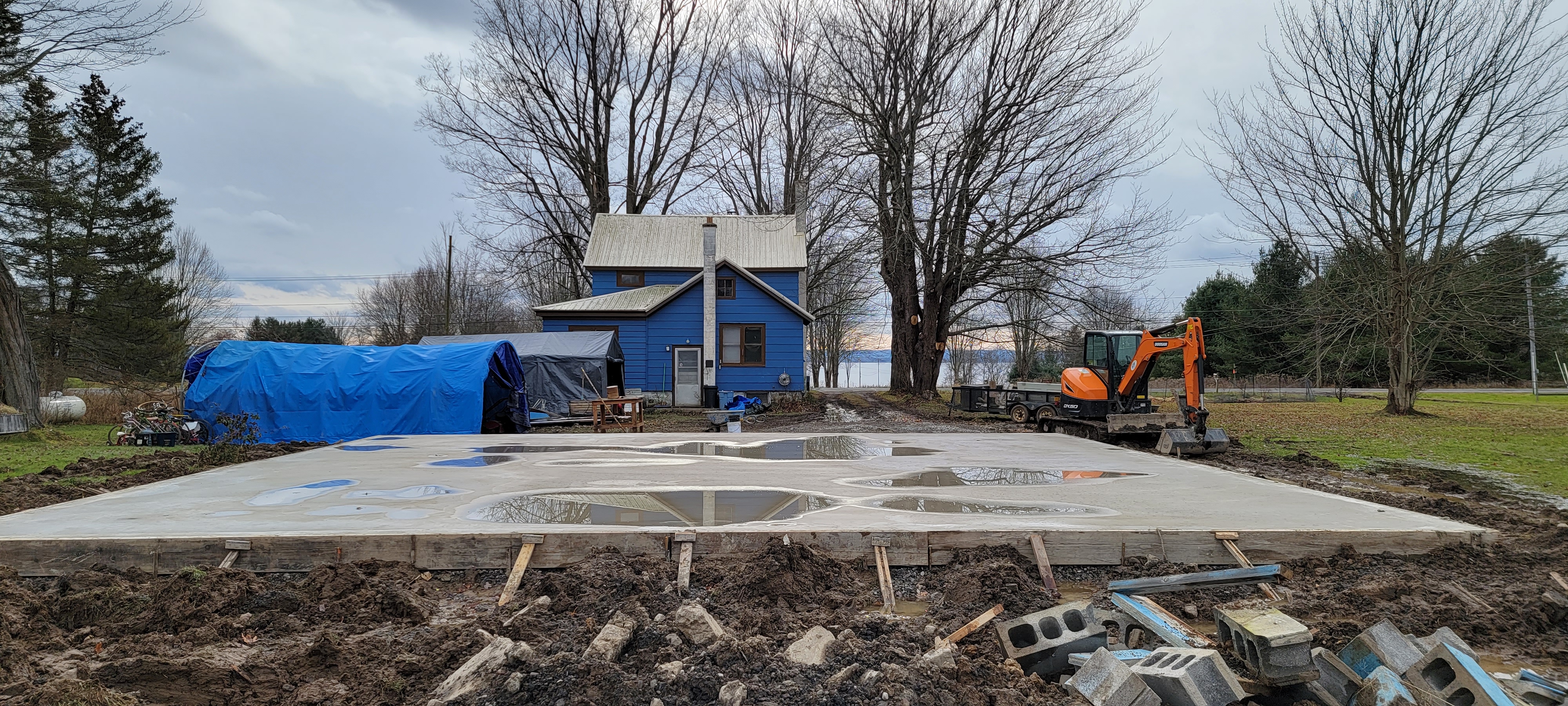 View of the house from the north, over the new concrete pad for the garage, facing south.